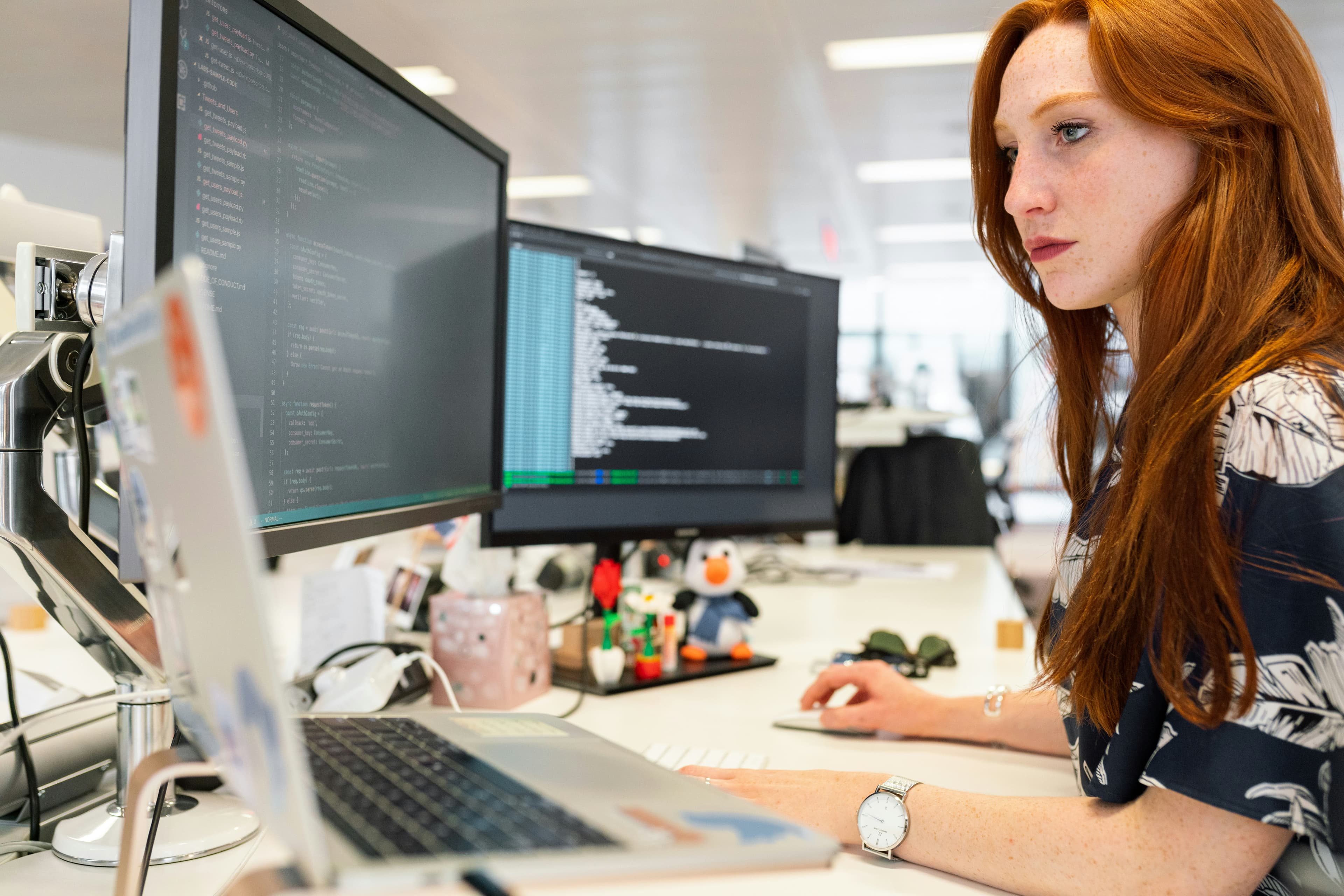 A software engineer focused on her computer screen at a desk, working through code or analysis