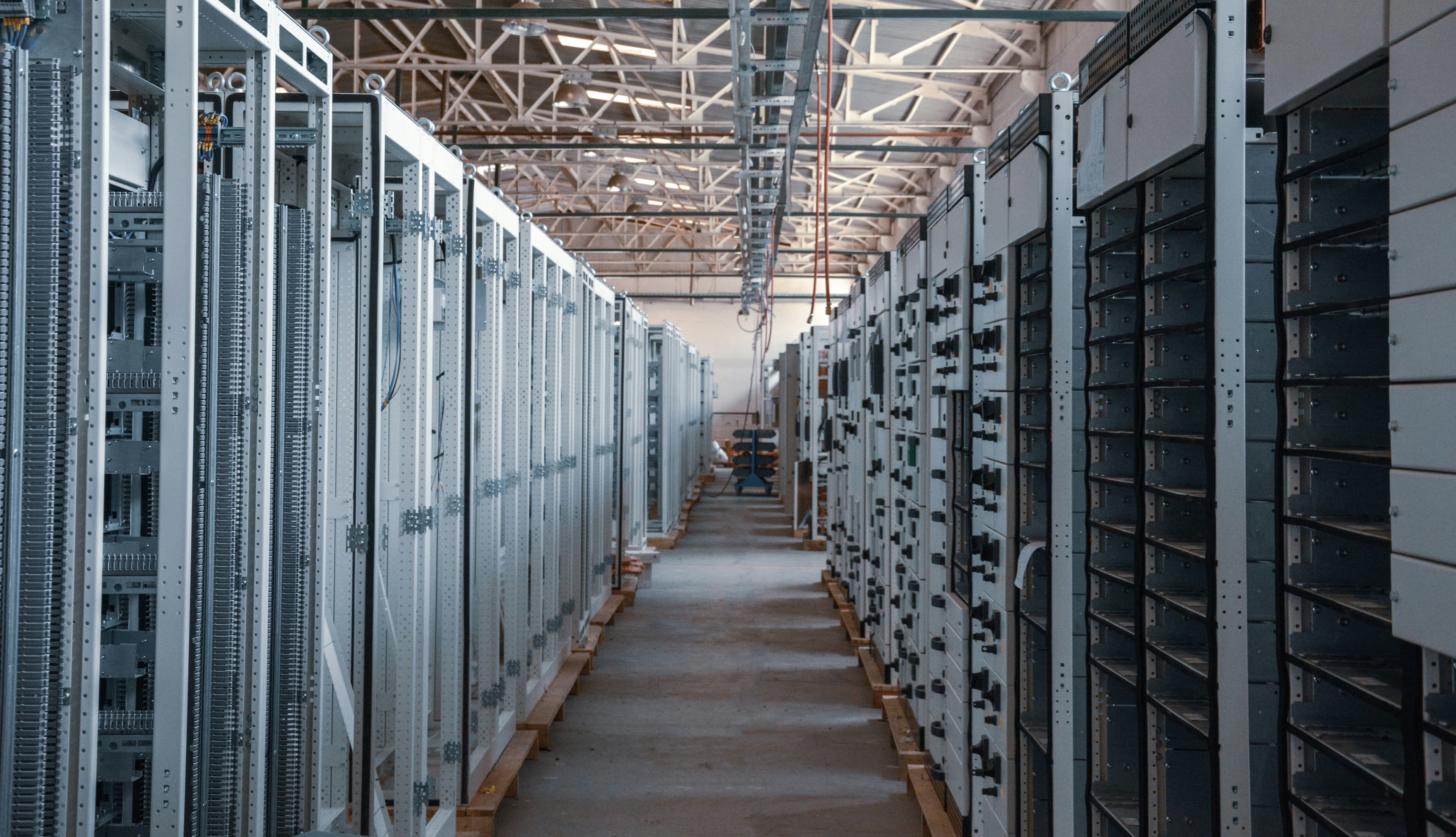 Wide view down a server room aisle lined with tall metal equipment racks on both sides