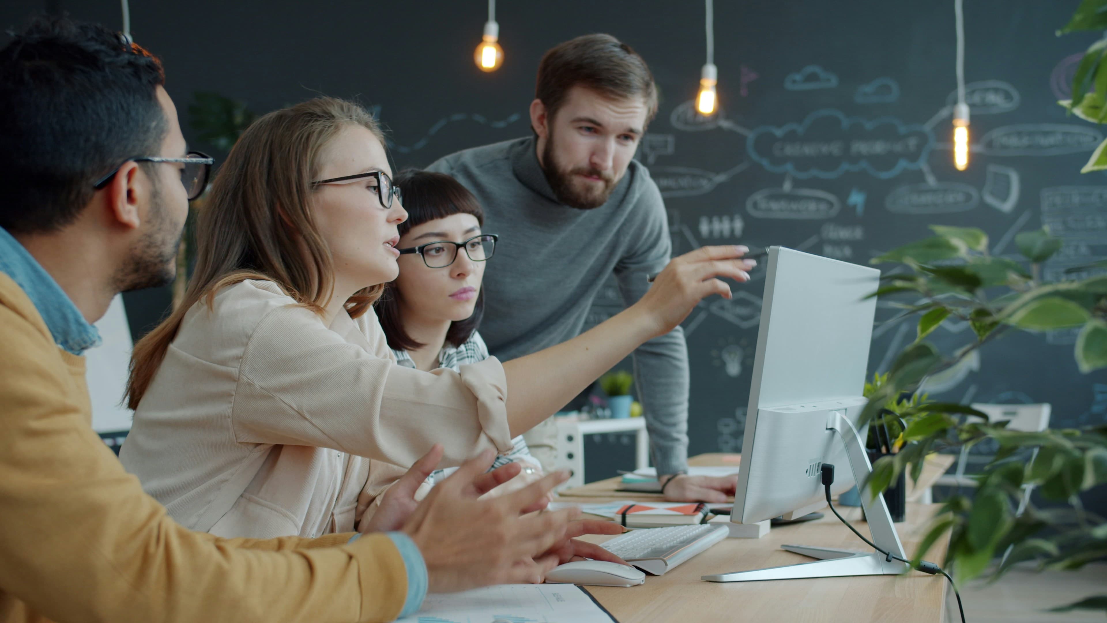 A small team gathered around a laptop, collaborating on a problem together