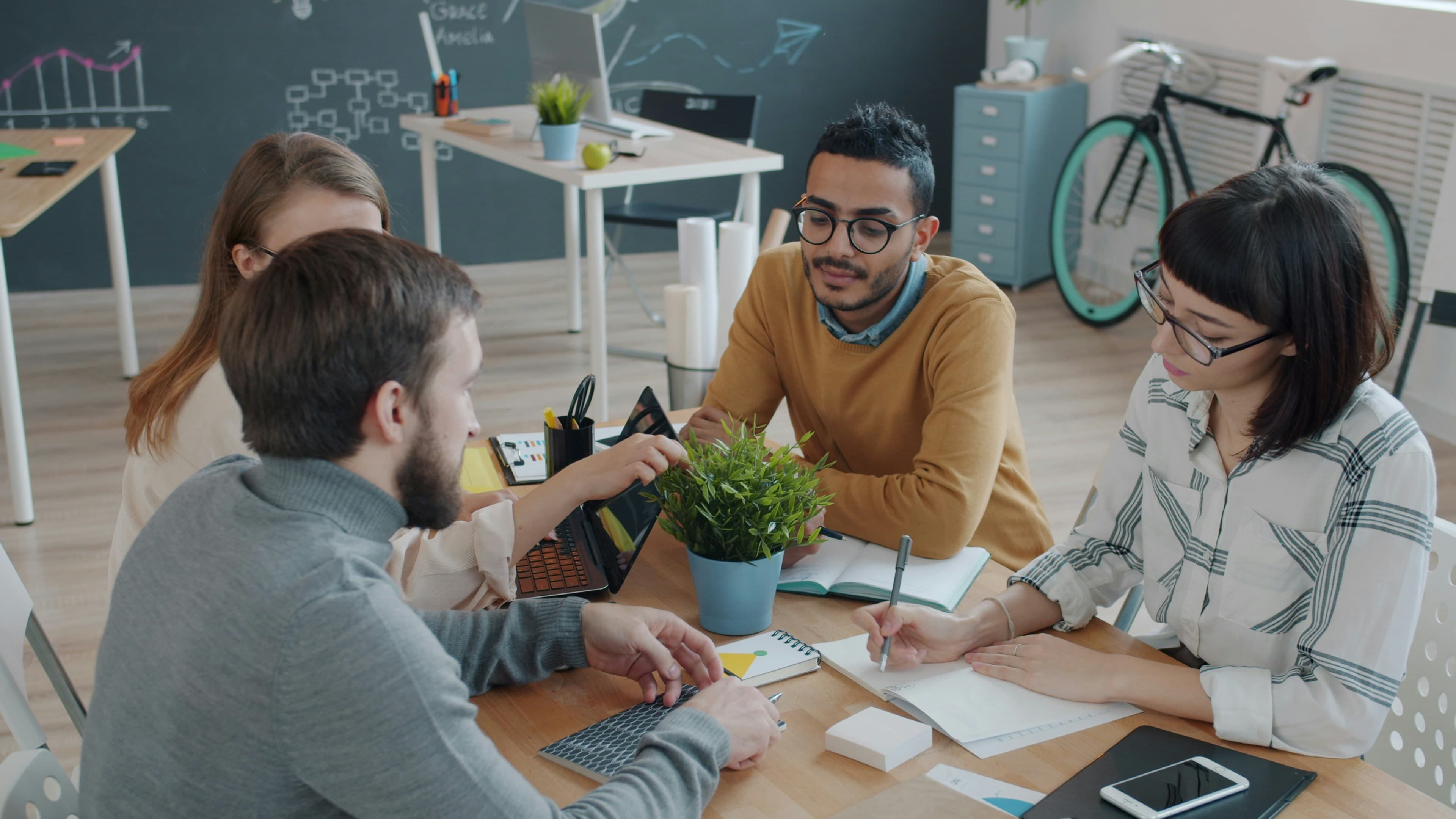 A diverse team of colleagues in discussion around a table in a modern office